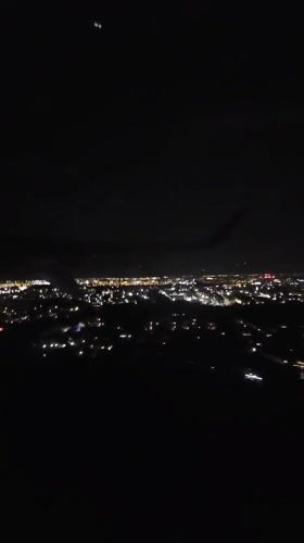 Passenger films nighttime aerial view of illuminated Bucharest from airplane