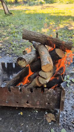 Backyard-style cookout in a Kharkiv park, grill burning.