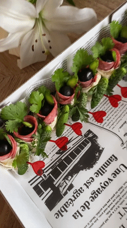 Rolled salami and cheese appetizers served on newspaper-lined platters