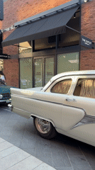 Vintage cars gather at upscale shopping district storefronts