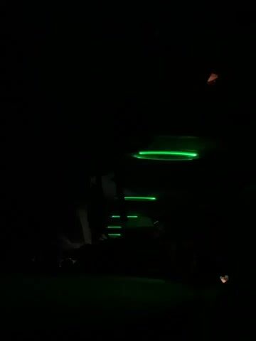 The video is recorded in a dark environment with bright green or blue lights that move sporadically. The camera also shifts position. It appears as if the lights are on a vehicle, as there are repeated glimpses of illuminated rectangular shapes. There is indistinct audio of musical music.