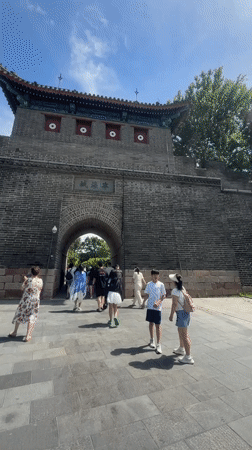 Tourists pass through an ornate historic gate in Qinhuangdao