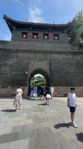Tourists pass through an ornate historic gate in Qinhuangdao
