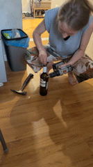 Woman uses power drill, hammer to open wine bottle