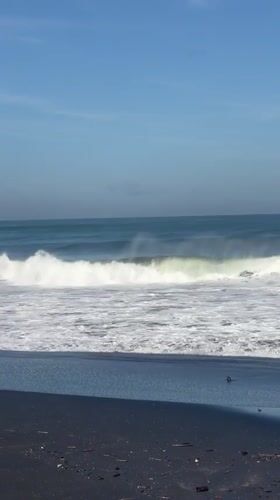 Early morning beach activity captured on Kediri's black sand shores