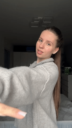 Young woman documents herself dancing, posing in Klin bedroom