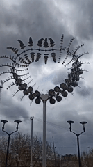 Kinetic sculpture with spinning metallic elements observed rotating outdoors