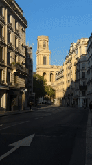 Ornate Paris street with stone facades, iron balconies, and a flag-draped storefront