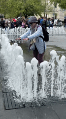 Woman plays in Budapest fountains during morning outing