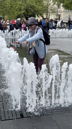 Woman plays in Budapest fountains during morning outing