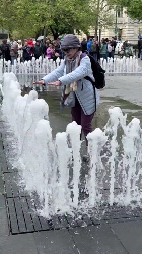 Woman plays in Budapest fountains during morning outing
