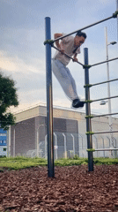Man performs calisthenics routine at outdoor gym equipment