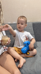Woman feeds young boy on couch in Rusanovo