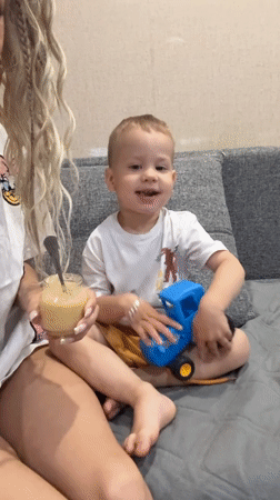 Woman feeds young boy on couch in Rusanovo
