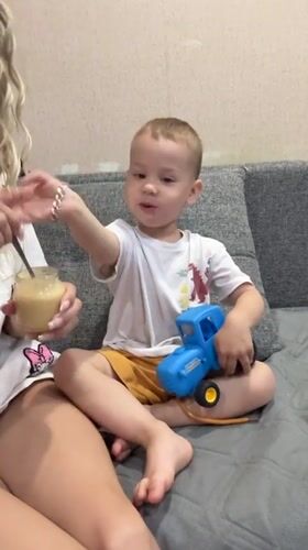 Woman feeds young boy on couch in Rusanovo