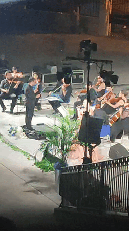 Outdoor orchestral concert under the night sky in Scordia