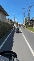 Moped rider travels narrow road in Tampaksiring, Indonesia