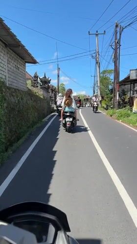 Moped rider travels narrow road in Tampaksiring, Indonesia