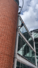 Two people descend pole from brick tower in Norwich