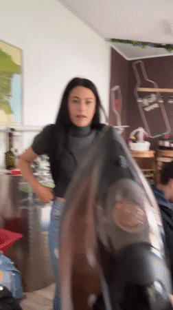 Woman irons blue fabric in Bulgarian classroom, poses playfully
