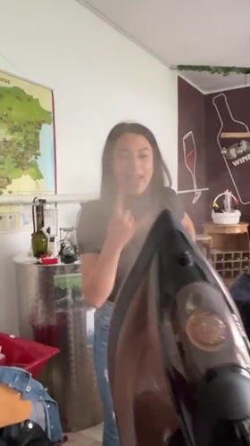 Woman irons blue fabric in Bulgarian classroom, poses playfully