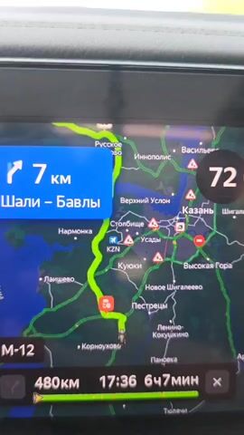 The video shows a car's navigation system. The screen displays a map with a green route, indicating the direction of travel. The system shows that the car is 7 kilometers away from the "Shali-Bavly" route. The current speed is 72 km/h, while the speed limit is 90 km/h. The distance to the destination is 480 kilometers. The estimated time of arrival is 17:36, with a total travel time of 6 hours and 47 minutes. The map shows the car's location near a town called "Kornoukhovo". Several red icons on the map indicate potential road issues in the Kazan area. Music is playing in the background.