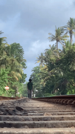 Person walks railway tracks amid Vesak decorations in Ahangama