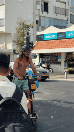 Man rides scooter with dog through Tel Aviv streets