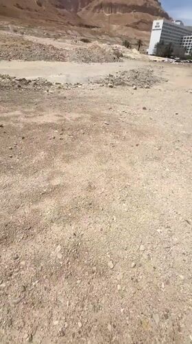 Person walks through arid Israeli desert near NEVO building