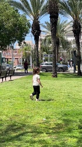 Girl plays, parakeets forage in Kiryat Bialik park