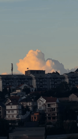 Illuminated cloud formation recorded over Da Lat hillside buildings