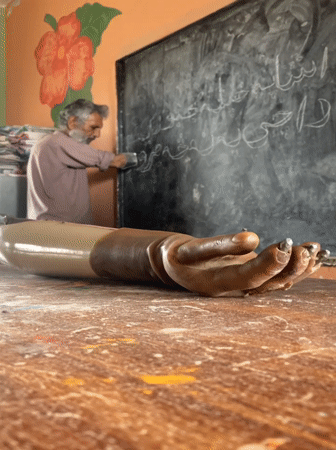 Elderly amputee teacher conducts lesson in Pakistani classroom