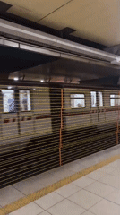Silver subway train arrives at tiled station platform