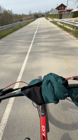 Cyclist rides red bicycle on guarded road near Djulunitsa