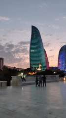 Flame Towers glow over Baku's waterfront promenade at dusk