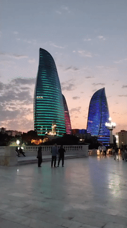 Flame Towers glow over Baku's waterfront promenade at dusk
