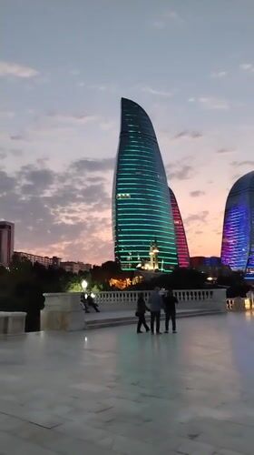 Flame Towers glow over Baku's waterfront promenade at dusk