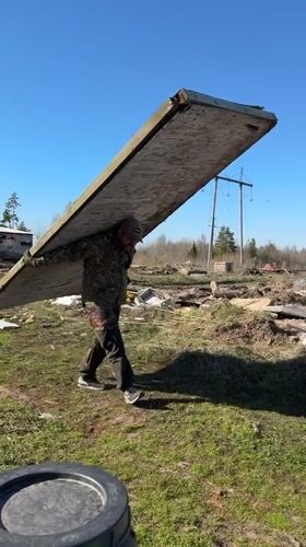 Man carries wooden plank across field in rural Russia