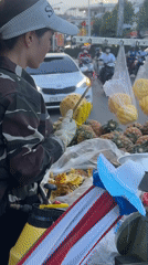 Street vendor prepares fresh pineapples amid motorcycle traffic Vietnam