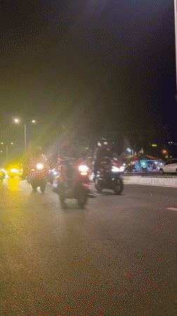 Nighttime motorcycle procession with Vietnamese flags observed on city streets