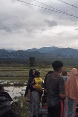 White car stuck in mud, rural Indonesia, people helping out