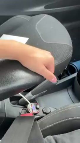 The video shows a car's interior, focusing on the center console and driver's seat. A person lifts the armrest, revealing a storage compartment filled with multiple round containers labeled "PABLO." The camera then pans around the interior, showing the steering wheel and dashboard briefly.