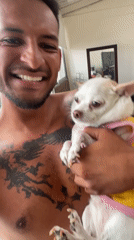 Man poses with small dog in pink shirt in Bogota