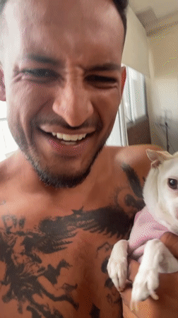 Man poses with small dog in pink shirt in Bogota