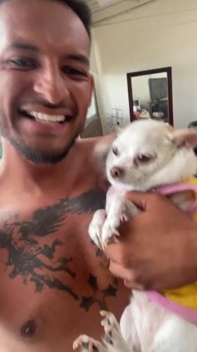Man poses with small dog in pink shirt in Bogota