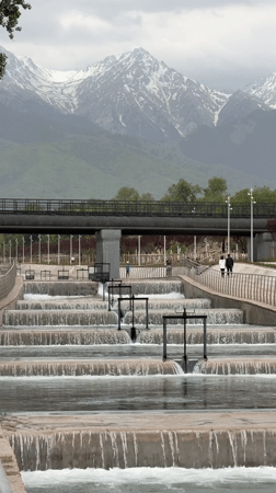 Park waterfall feature observed in Almaty amid mountain backdrop