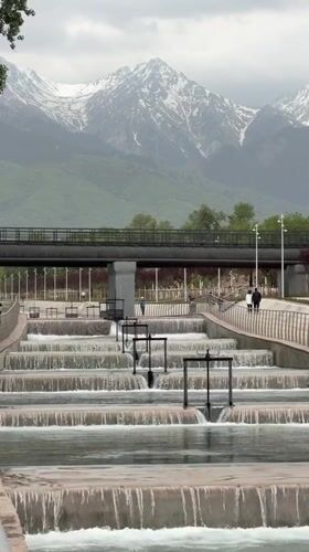 Park waterfall feature observed in Almaty amid mountain backdrop
