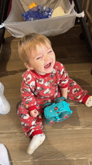 Toddler in holiday pajamas sits on wooden floor in Russia
