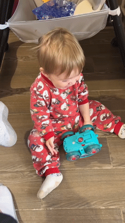 Toddler in holiday pajamas sits on wooden floor in Russia