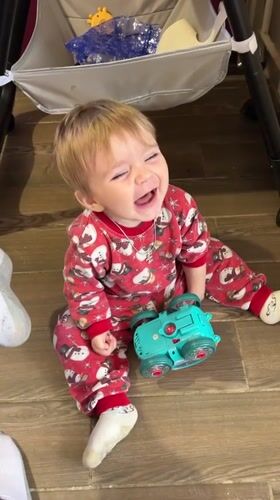 Toddler in holiday pajamas sits on wooden floor in Russia